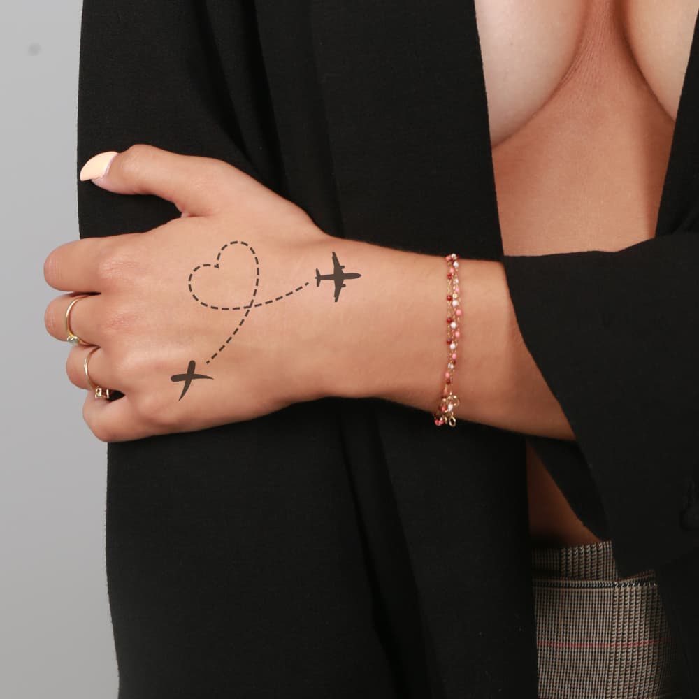 Tatouage voyage avion avec coeur pour femme sur la main